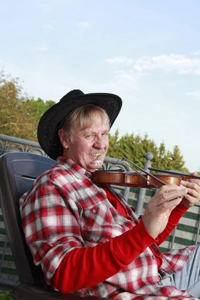 一个成熟的男人在阳台上拉小提琴 — 图库照片