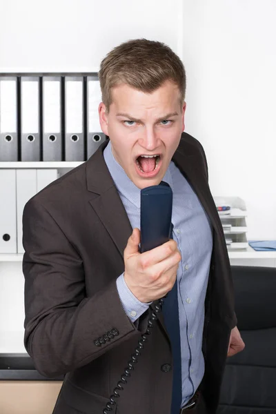 Joven Hombre Negocios Parado Oficina Gritando Por Teléfono Fondo Hay —  Fotos de Stock