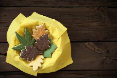 Different Autumnal Cookie Leaves in a Yellow Bowl on Wood clipart