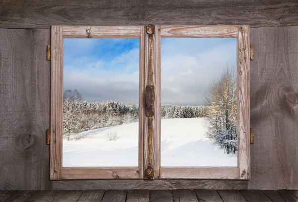 Snowy winter landscape in january. View out of an old rustic wooden window.