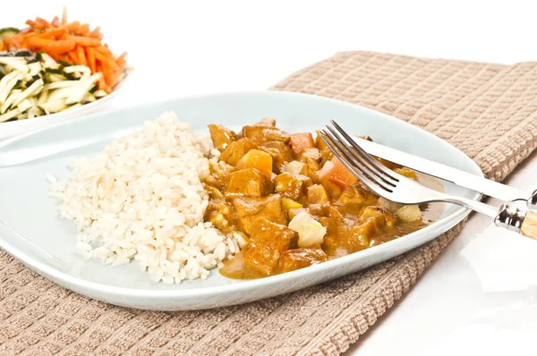 turkey goulash with buttered rice and fruit sauce served on a light blue plate with holzbesteck