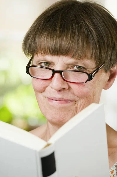 Портрет Пожилой Женщины Очках Чтения Открытой Книге Дружелюбной Улыбкой Камеру — стоковое фото