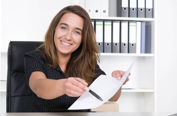 Молода Усміхнена Жінка Сидить Столом Офісі Вказуючи Ручкою Аркуш Паперу — стокове фото