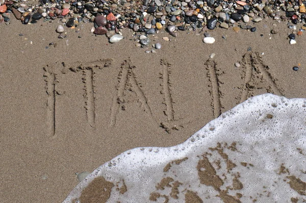 砂のビーチで小石と波でイタリア語をレタリング — ストック写真