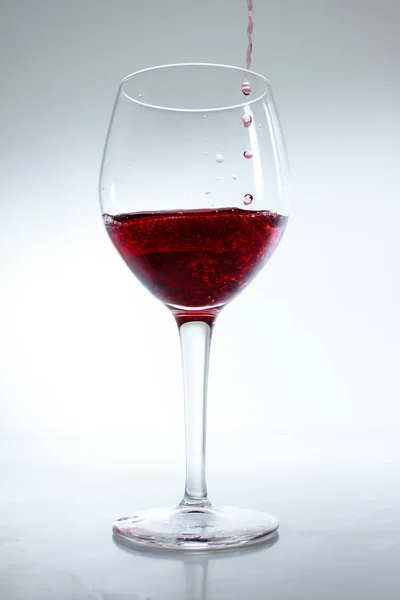 Kırmızı Şarap Beyaz Arka Planda Bir Bardağa Döküldü — Stok fotoğraf