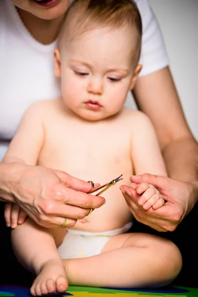 Mãe Cortando Unhas Nas Mãos Seu Bebê Sentado Chão Banheiro — Fotografia de Stock