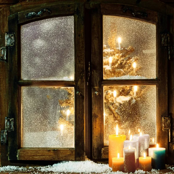 ログキャビンのクリスマスウィンドウを歓迎します 窓辺には燃えるキャンドルのグループと 霜降りのパンを通して見える輝くクリスマスツリーがあります — ストック写真