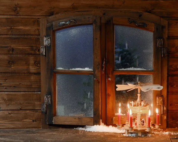 クリスマスの休日の季節の素朴な木製の窓のペインで側に雪の少量のスタンドに輝く赤いキャンドル — ストック写真