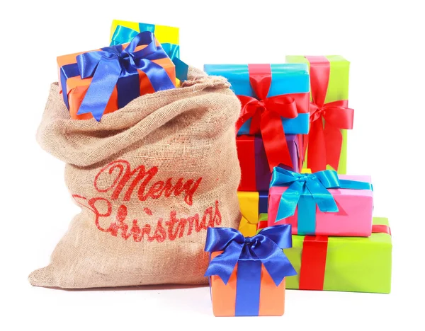 カラフルなクリスマスの背景には サンタのギフト袋には 色とりどりのギフトでいっぱいのクリスマスボックスと白い上に装飾弓で結ばれたプレゼントがあります — ストック写真
