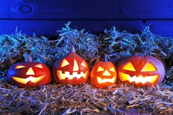 Four Illuminated Halloween Pumpkins Straw Front Old Weathered Wooden Boards — Stock Photo, Image