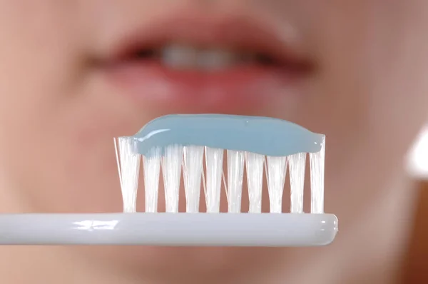 toothbrush before blurred illustrated face of a young woman symbolizing dental care