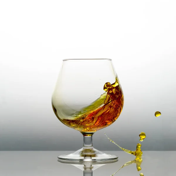 Cognac Splashing Out Glass Table — Stock Photo, Image