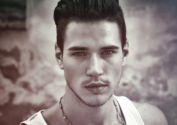 Headshot of attractive black haired young man outside, looking at camera