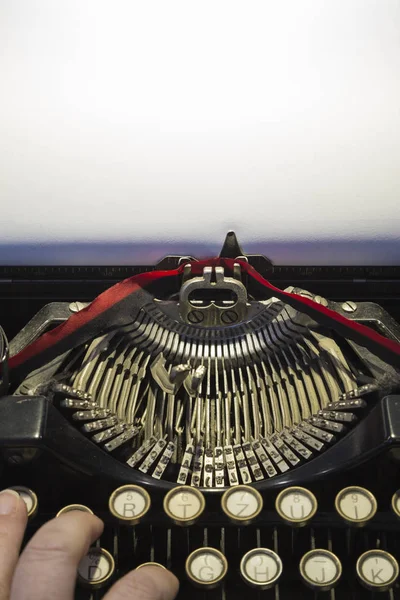 antique old typewriter with hand and empty sheet in portrait