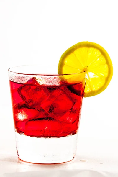 ビューにちりばめられたガラス 氷で赤い液体で満たされました 明るい光の中でレモンのスライスを装飾したMt — ストック写真