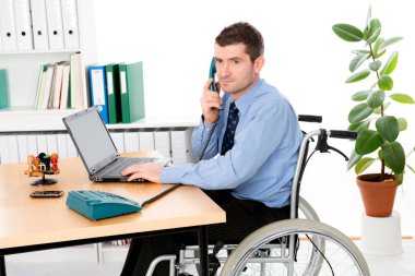 man in wheelchair is working in the office clipart