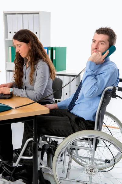 坐在轮椅上的男人和他的女同事在办公室工作 — 图库照片