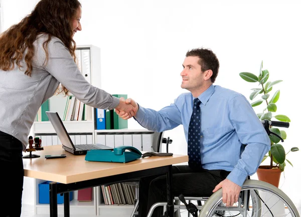 man in wheelchair is greeting a woman in the office