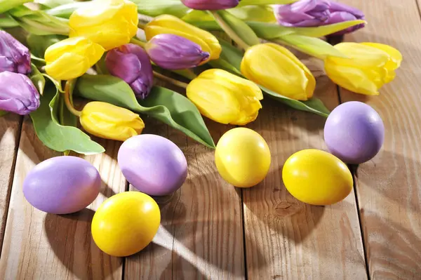 Lila Und Gelbe Ostereier Mit Tulpen Auf Altem Holzboden — Stockfoto