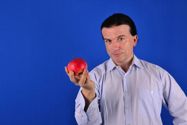 Młody Człowiek Czerwonym Jabłkiem Niebieskim Tle — Zdjęcie stockowe