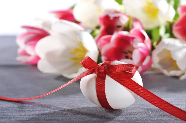 Bílé Velikonoční Vejce Červenou Stuhou Tulipány Pozadí — Stock fotografie