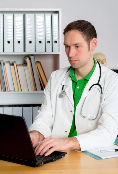 Jeune Médecin Famille Dans Son Bureau Travaille Avec Ordinateur Photos De Stock Libres De Droits