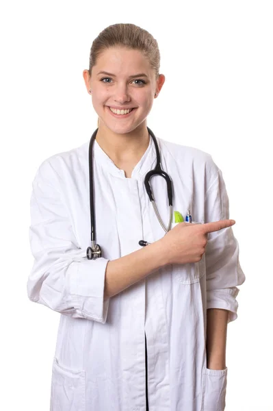 Female Doctor White Coat Smiling Camera Pointing Right Her Index — Stock Photo, Image