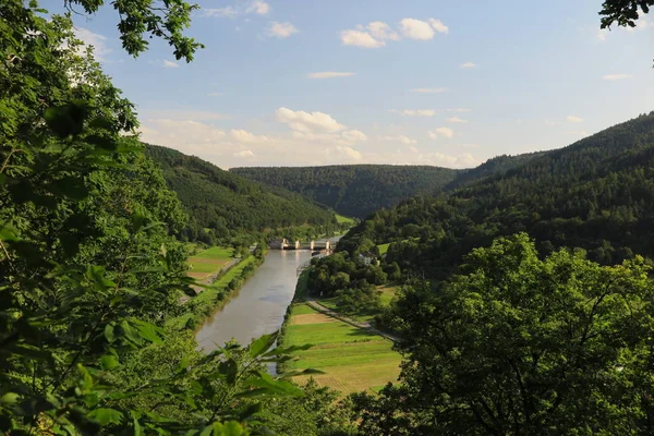 stock image View down from Teufelskanzel of Kranichsberg hill to Neckar weir. Nice perspective that combines a weir in a romantic river valley with hills, woods, meadows, blue sky, sunshine, and fair-weather clouds.