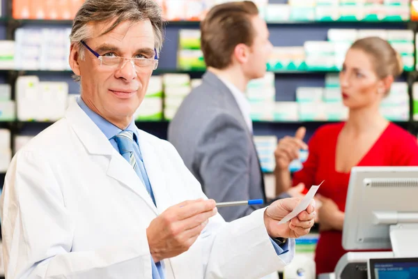 Φαρμακοποιός Στο Φαρμακείο Του Μια Συσκευασία Φαρμάκων Στο Παρασκήνιο Πελάτη — Φωτογραφία Αρχείου