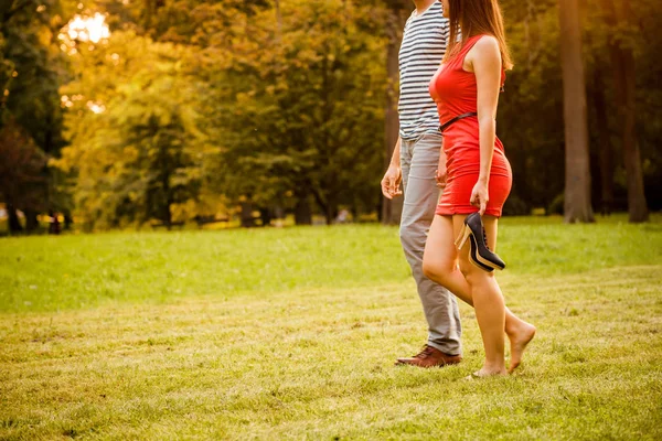 对夫妇走在草丛中 女人是光着脚抱着高跟鞋鞋 — 图库照片