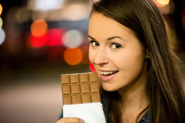 Jovem Mulher Comendo Chocolate Rua Com Luzes Néon Noite — Fotografia de Stock