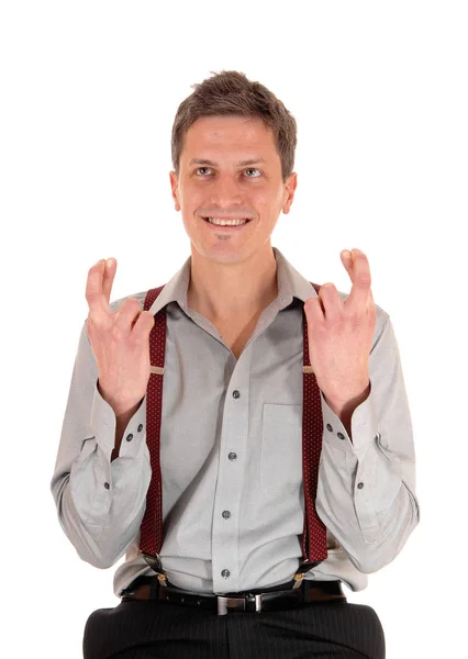 一个笑容满面的年轻人 穿着一件灰色的衬衫 举起双手 交叉着手指 被白色的背景隔开了 — 图库照片