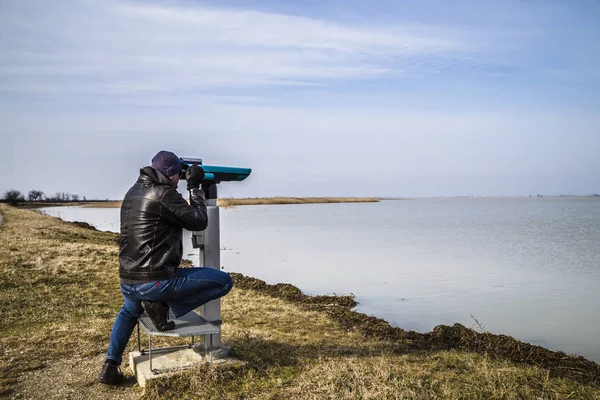 通过双筒望远镜好奇地看着湖面的温文尔文人 — 图库照片