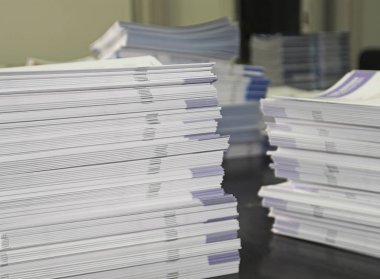 Piles of handout papers lying on a table. clipart