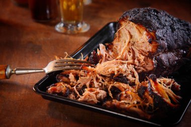 Close up Appetizing Pulled Pork on Black Tray with Fork on Top of Wooden Table. clipart