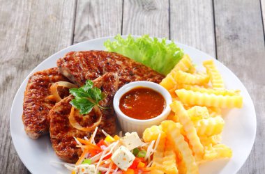 Close up Appetizing Fried Escalope with Potato Fries on White Plate, Served on Wooden Table. clipart
