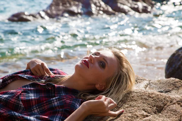 岩の多いビーチでフランネルシャツの女の子 — ストック写真
