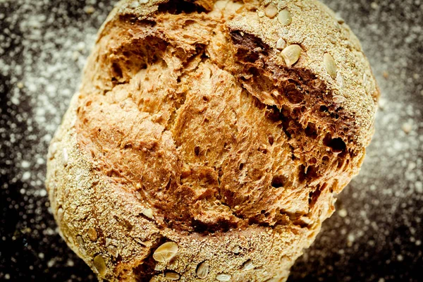 Rustic round traditional baked bread made of wheat flour with crispy crust and sunflower and pumpkin seeds, high-angle close-up