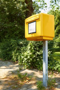 a yellow mailbox stands at the edge of a path. clipart