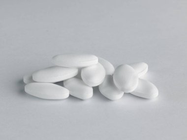 a pile of white lozenge shaped pills on a white background clipart