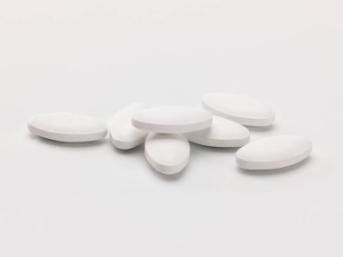a pile of white lozenge shaped pills on a white background clipart