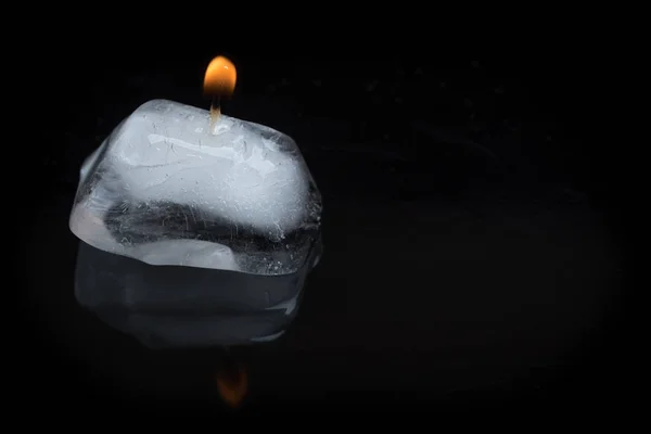 点亮的蜡烛芯的特写镜头 在黑色背景上粘在冰立方上 带有反射 — 图库照片