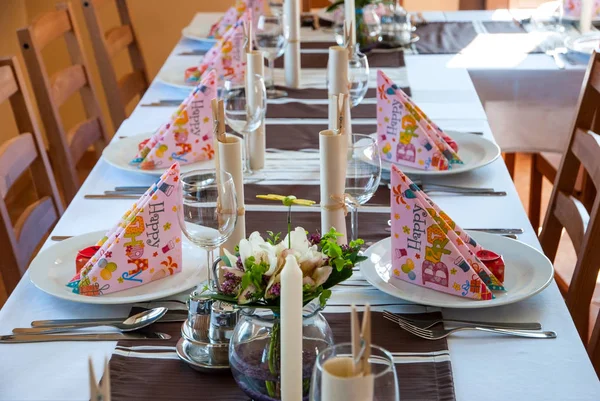 Birthday table decoration with plates, glasses, napkins and flowers