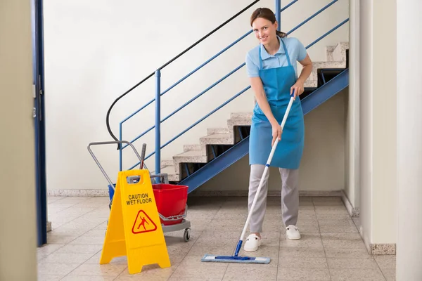 Junge Glückliche Arbeiterinnen Mit Reinigungsgeräten Und Nassen Fußbodenschildern — Stockfoto