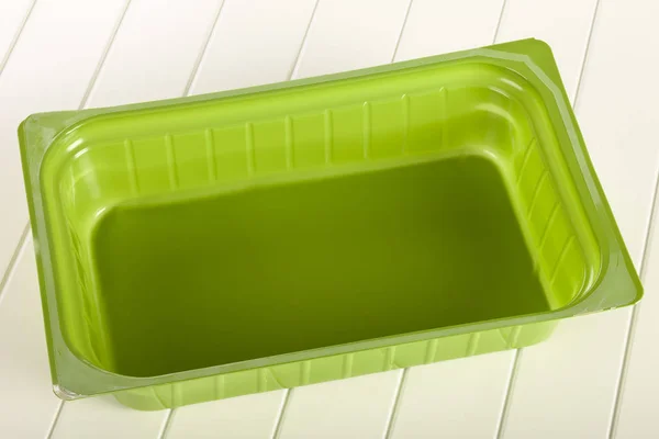 Groene Plastic Mal Een Witte Houten Achtergrond — Stockfoto