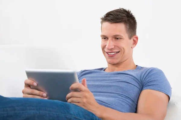 Šťastný Muž Při Pohledu Digitální Tablet Při Ležení Pohovce — Stock fotografie
