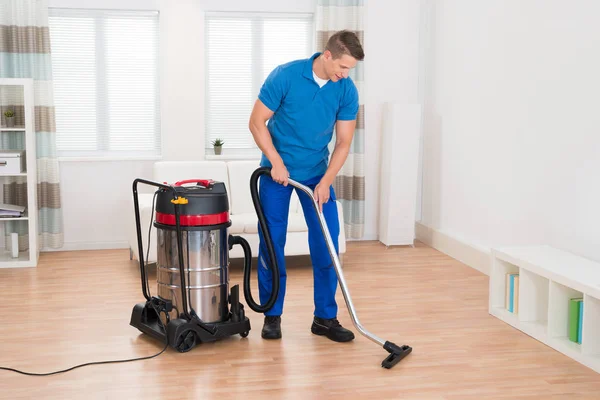 Szczęśliwy Mężczyzna Woźny Vacuuming Drewniana Podłoga Domu — Zdjęcie stockowe