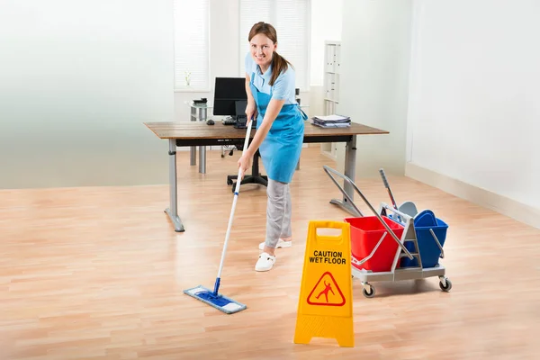 Happy Female Janitor Cleaning Equipments Cleaning Hardwood Floor Office — стоковое фото