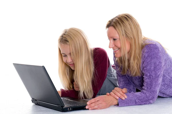 金髪の女の子と母親が床に横になってノートパソコンを使って — ストック写真