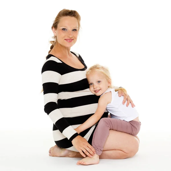 在白色背景下拥抱怀孕母亲的小女孩 快乐的家庭 — 图库照片